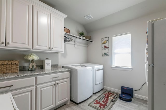 laundry area with light wood-type flooring, visible vents, cabinet space, baseboards, and washing machine and clothes dryer