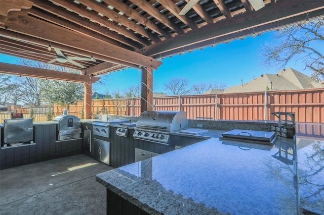 view of patio / terrace featuring a ceiling fan, area for grilling, a fenced backyard, and an outdoor kitchen