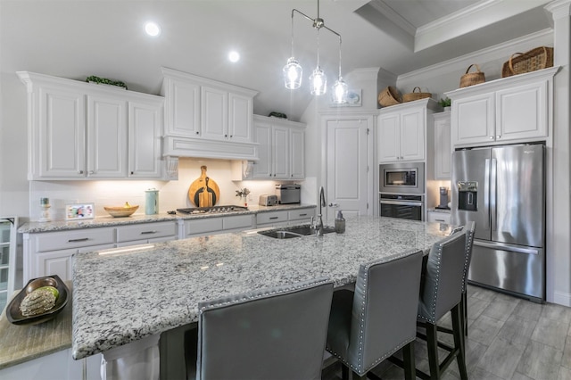 kitchen with ornamental molding, a sink, stainless steel appliances, white cabinets, and decorative backsplash