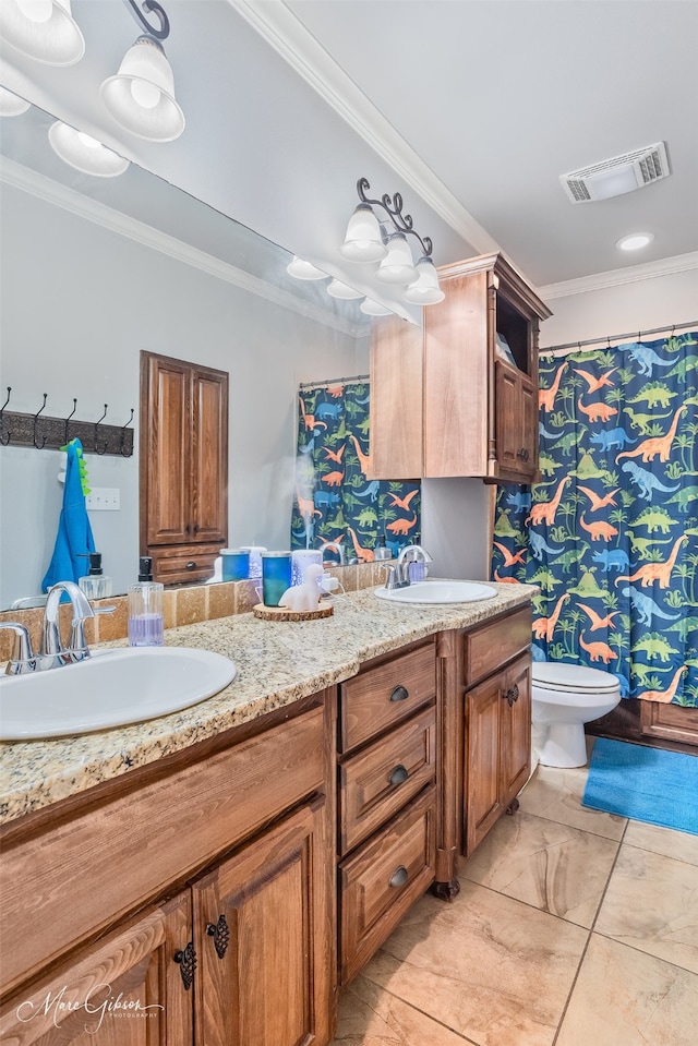 bathroom with a sink, visible vents, double vanity, and crown molding