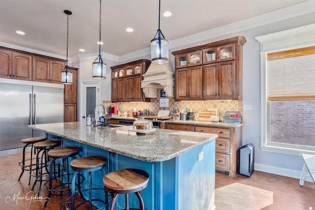 kitchen with decorative backsplash, built in refrigerator, a kitchen bar, and a sink