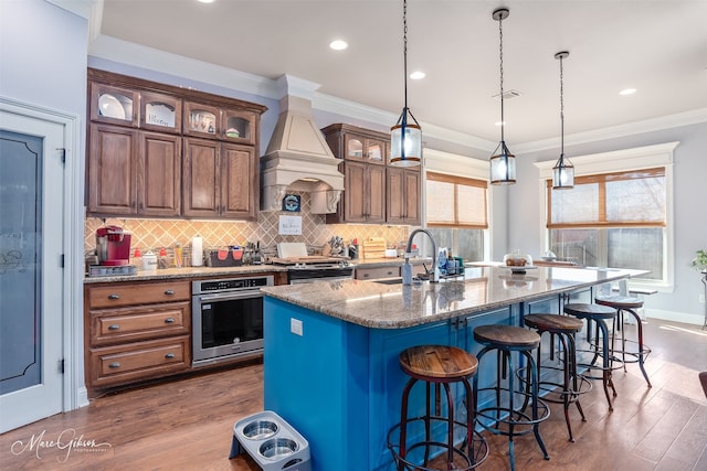 kitchen with visible vents, a breakfast bar, a sink, appliances with stainless steel finishes, and custom exhaust hood