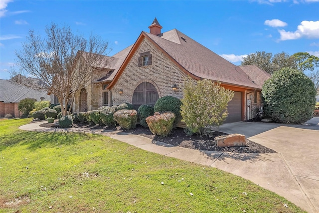 view of front of house with driveway, an attached garage, a shingled roof, a front yard, and brick siding