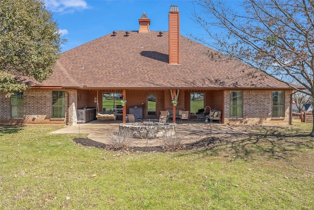 rear view of property with a patio area, a lawn, an outdoor fire pit, and a shingled roof