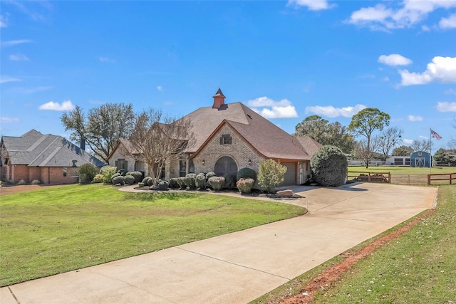 view of front of house featuring a front yard, brick siding, a garage, and driveway