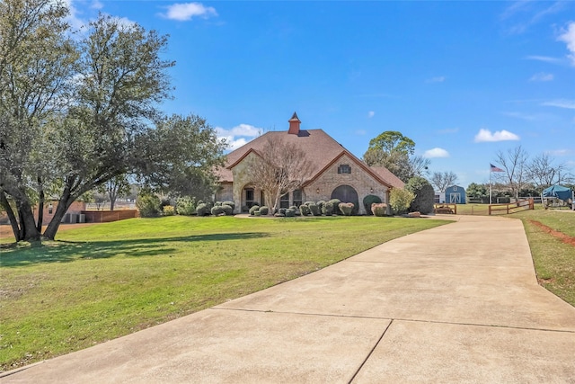 french country home with a front lawn, stone siding, and driveway