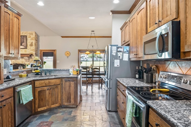 kitchen with dark stone countertops, stone tile floors, a peninsula, appliances with stainless steel finishes, and backsplash