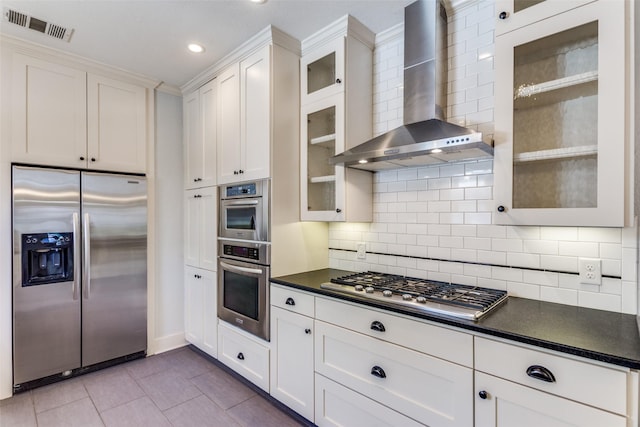 kitchen featuring visible vents, dark countertops, appliances with stainless steel finishes, white cabinets, and wall chimney range hood