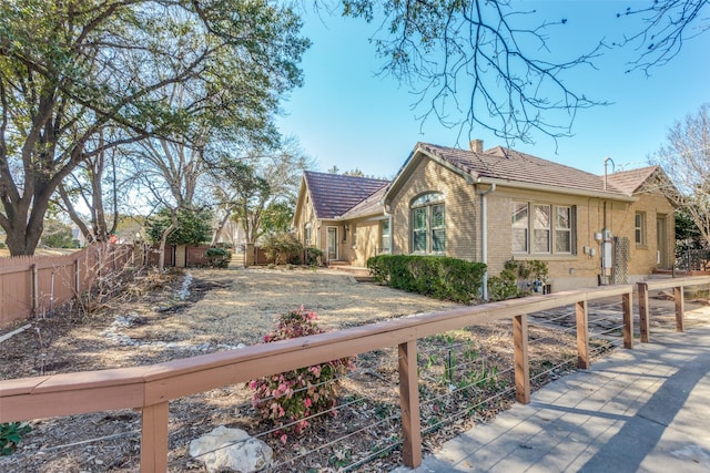 view of property exterior with brick siding, a chimney, and fence private yard