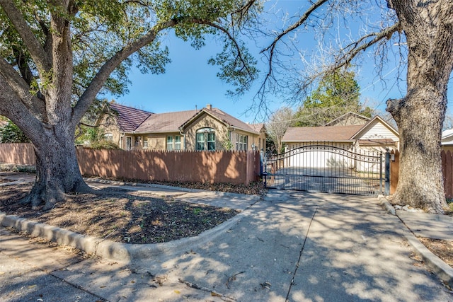 view of front of property featuring a fenced front yard, a tile roof, and a gate