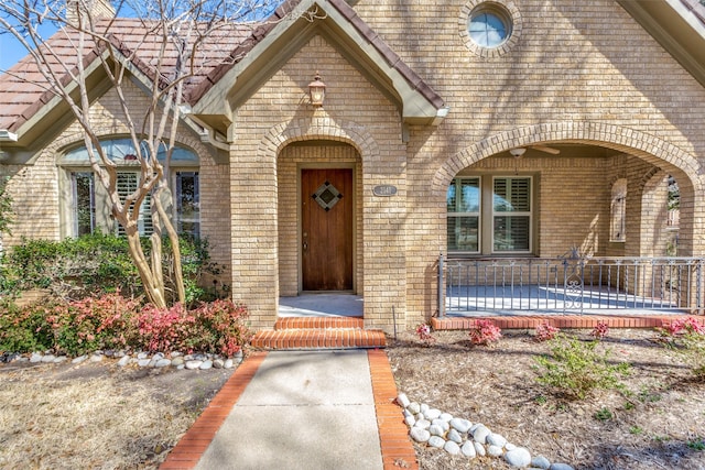 view of exterior entry with brick siding and covered porch