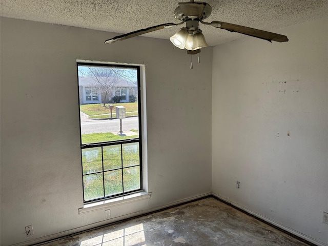 spare room with a wealth of natural light, a textured ceiling, and concrete floors