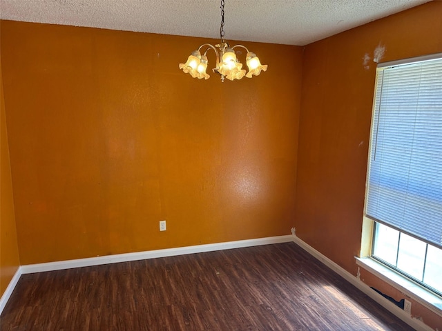 unfurnished room featuring dark wood-type flooring, a notable chandelier, baseboards, and a textured ceiling