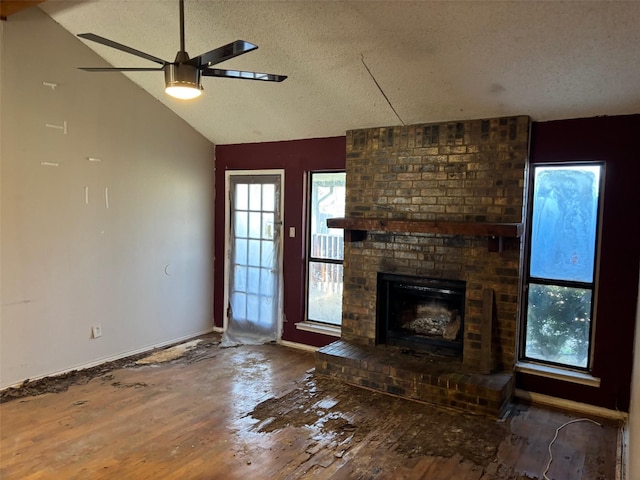 unfurnished living room featuring wood finished floors, lofted ceiling, a fireplace, ceiling fan, and a textured ceiling