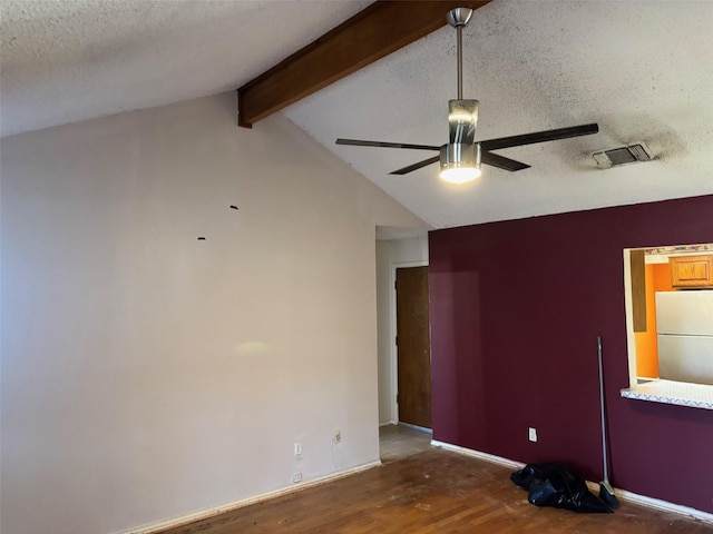 empty room with a textured ceiling, lofted ceiling with beams, ceiling fan, and wood finished floors