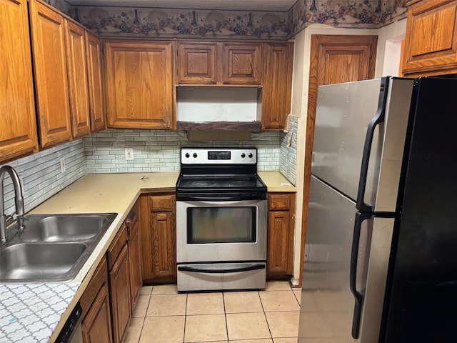 kitchen with under cabinet range hood, appliances with stainless steel finishes, brown cabinetry, and a sink