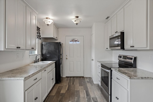 kitchen featuring white cabinets, wood finished floors, appliances with stainless steel finishes, and a sink