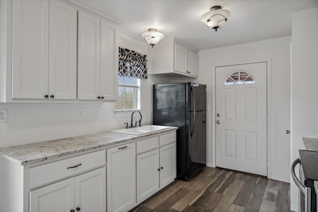 kitchen with stainless steel range with electric stovetop, a sink, dark wood-style floors, white cabinetry, and freestanding refrigerator