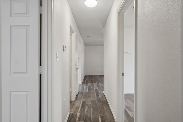 hall featuring baseboards and dark wood finished floors