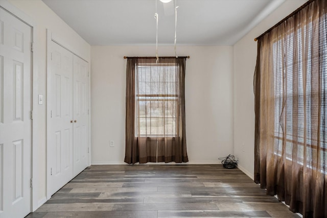 unfurnished dining area with baseboards and wood finished floors