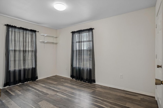 empty room with dark wood-type flooring and baseboards