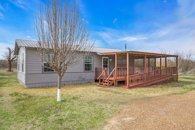 rear view of property with a lawn, metal roof, and a sunroom