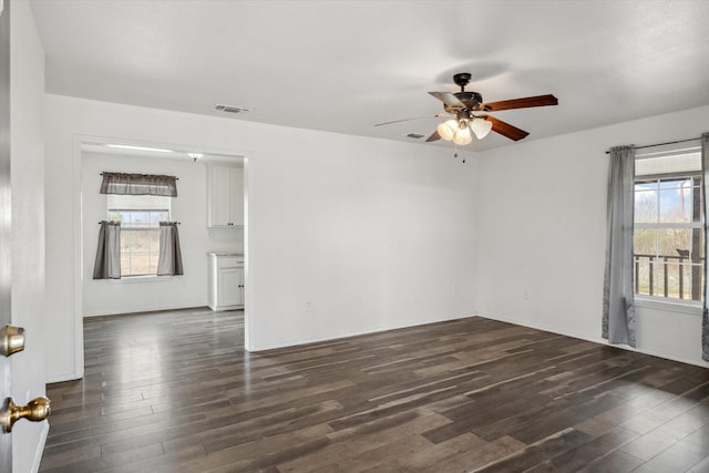 unfurnished room featuring visible vents, baseboards, dark wood-type flooring, and ceiling fan