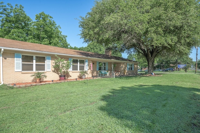 view of front of home with brick siding, a chimney, and a front lawn