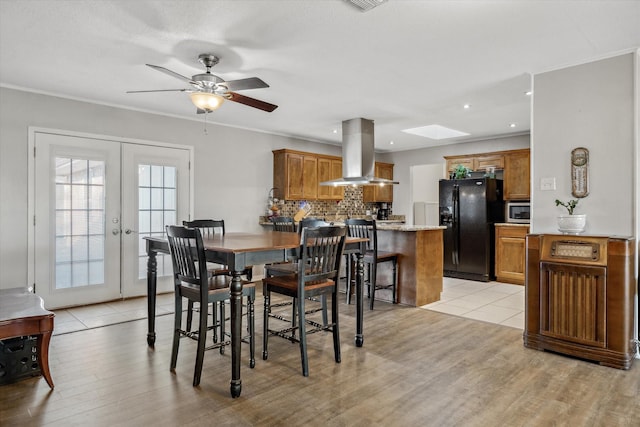 dining space with ornamental molding, french doors, light wood-style floors, a skylight, and ceiling fan