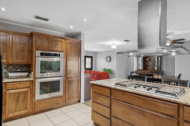 kitchen featuring light tile patterned floors, visible vents, island exhaust hood, ceiling fan, and stainless steel appliances