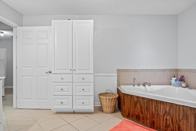 bathroom with tile patterned flooring, wainscoting, and a garden tub