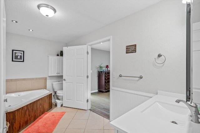 full bath featuring vanity, a bath, wainscoting, tile patterned floors, and toilet