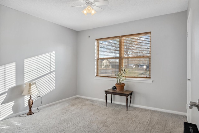 spare room with carpet flooring, ceiling fan, a textured ceiling, and baseboards