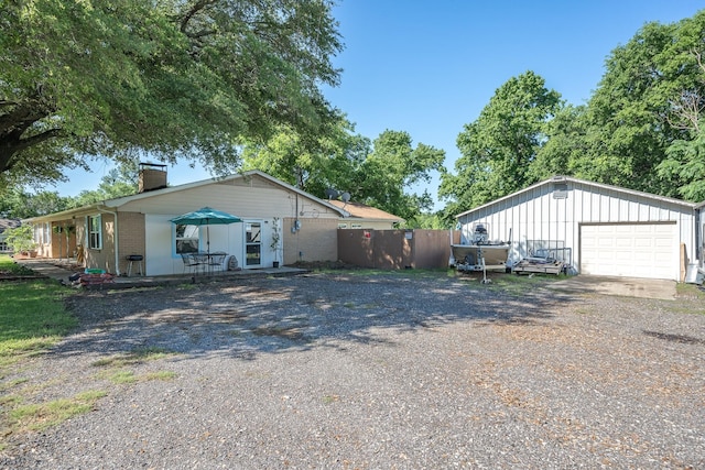 view of front of property featuring driveway, fence, a garage, brick siding, and a chimney