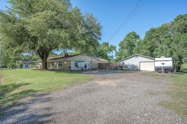 view of front of home featuring a front yard, an outbuilding, fence, a chimney, and a detached garage