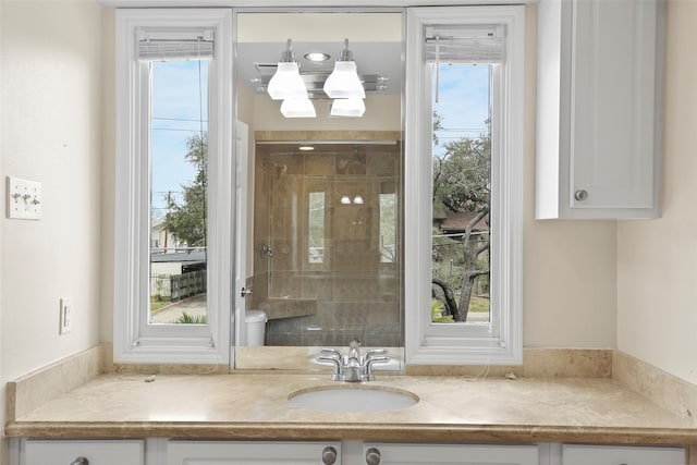 bathroom featuring a wealth of natural light, tiled shower, and vanity