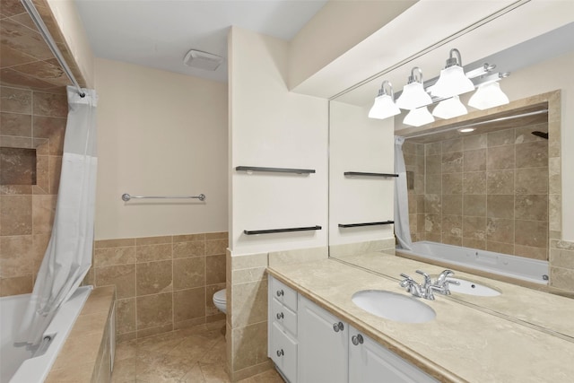 full bath with tile patterned flooring, toilet, vanity, tile walls, and tiled shower / bath