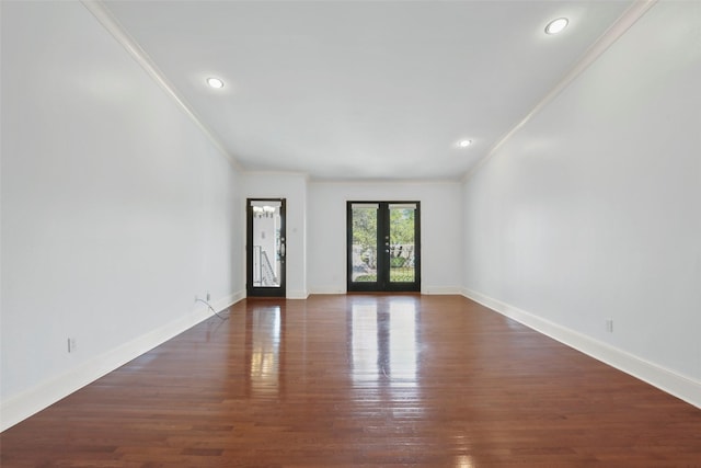 empty room with wood finished floors, french doors, baseboards, and ornamental molding