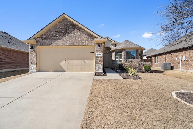 view of front of property with brick siding, a garage, driveway, and central AC