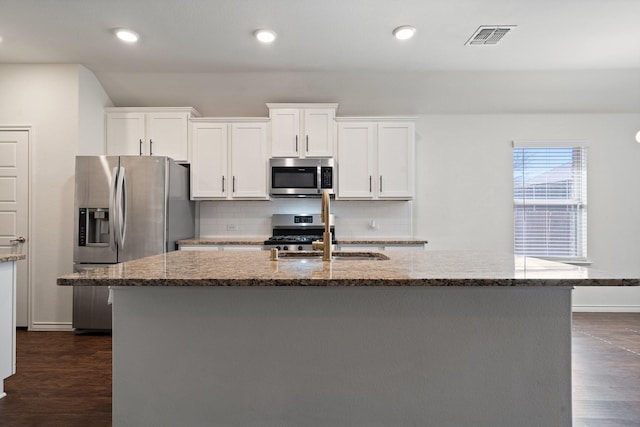 kitchen with visible vents, dark wood-type flooring, a sink, tasteful backsplash, and stainless steel appliances