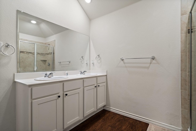 full bath featuring double vanity, a stall shower, wood finished floors, and a sink