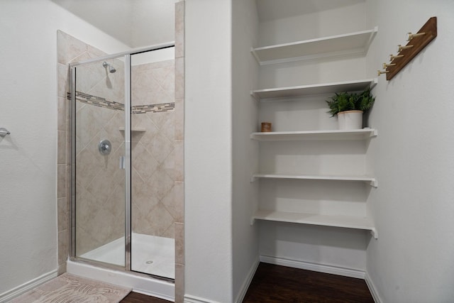 bathroom with a shower stall and baseboards