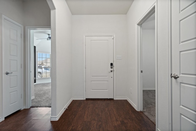 hall with baseboards, arched walkways, and dark wood-style flooring