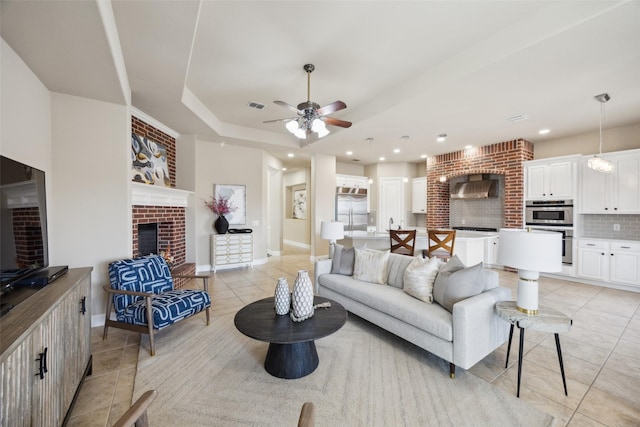 living room featuring visible vents, baseboards, light tile patterned flooring, a fireplace, and a raised ceiling