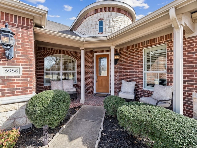 view of exterior entry with covered porch and brick siding