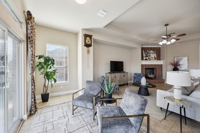 living area with baseboards, visible vents, tile patterned flooring, a raised ceiling, and a brick fireplace