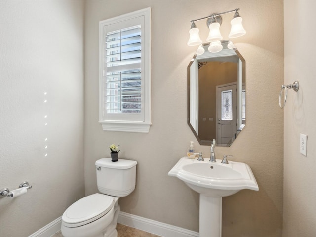 half bath with tile patterned floors, toilet, and baseboards