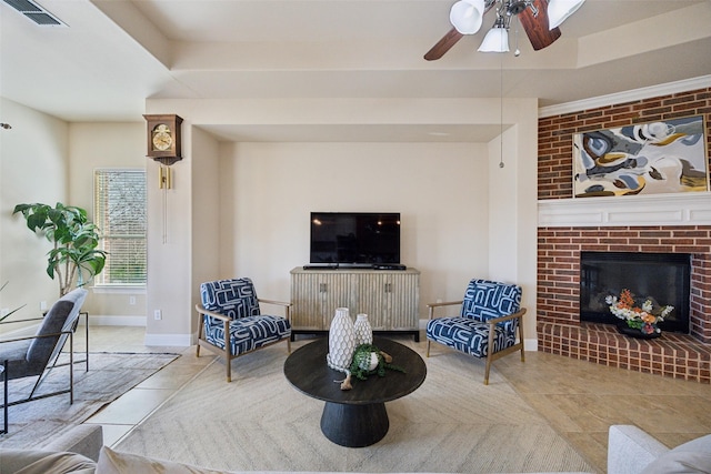 tiled living area featuring visible vents, a tray ceiling, baseboards, a brick fireplace, and ceiling fan