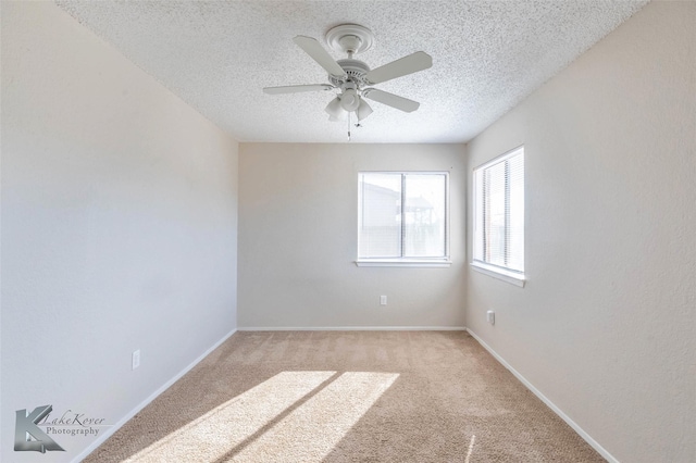 empty room with a textured ceiling, ceiling fan, baseboards, and light carpet