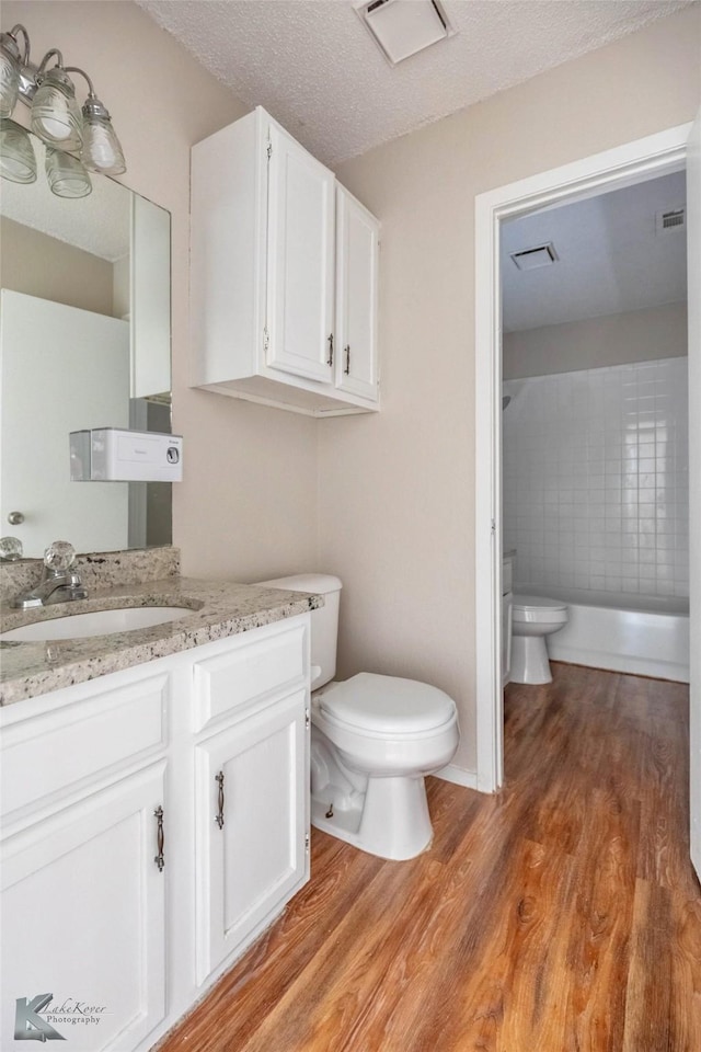 bathroom featuring vanity, toilet, wood finished floors, and visible vents